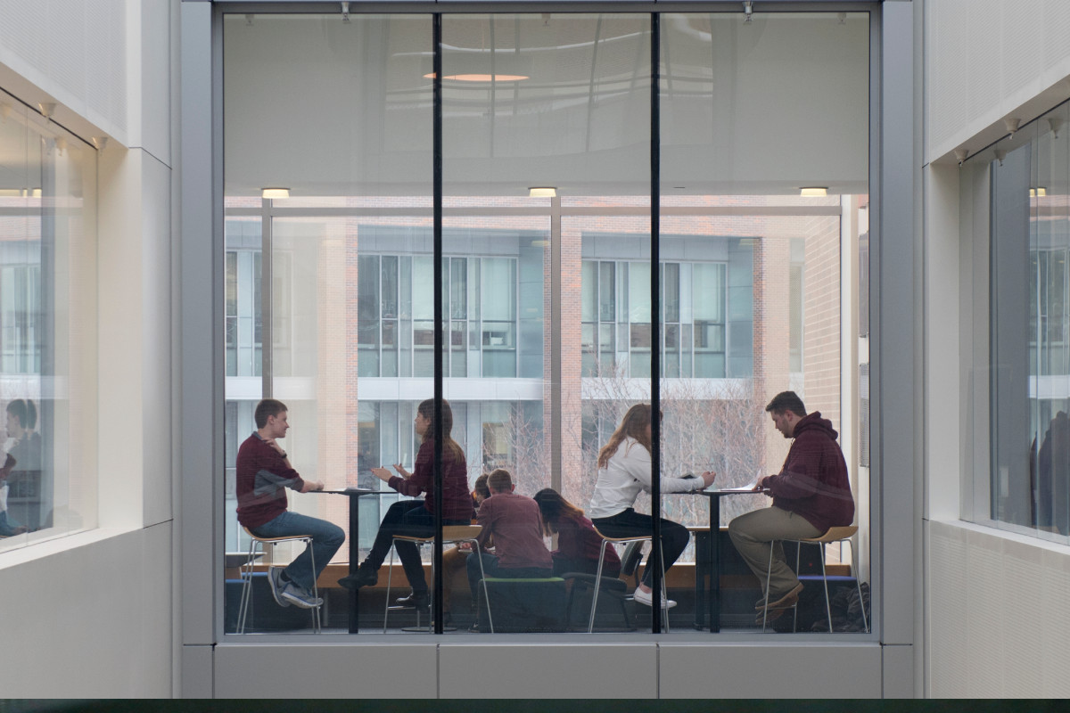 Students study at tables across a skyway